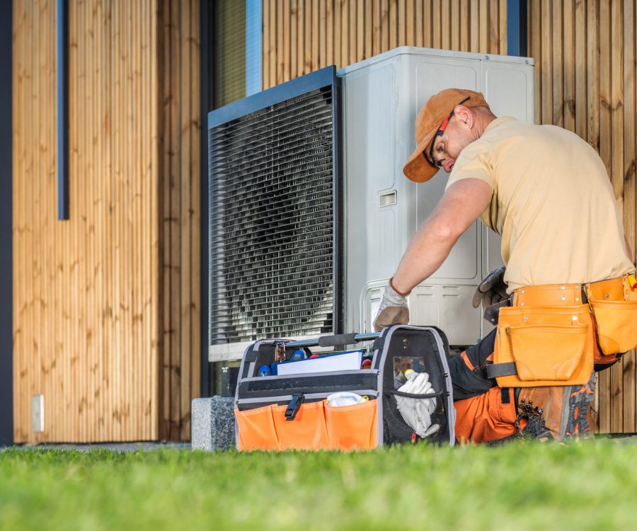 HVAC worker working on a modern heat pump outside a house.